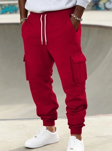 Detail of red cargo joggers featuring drawstring waist and large side flap pockets