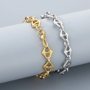 Macro detail of gold and silver stainless steel chain bracelets with lobster clasp closure