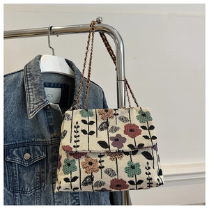 Detail of vintage floral embroidered woven shoulder bag with metal chain strap