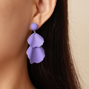Close-up of purple matte petal earrings worn by a model for a creative fashion look