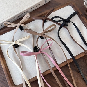 Detail of leather bow hair claws in various colors on a wooden tray with ribbons