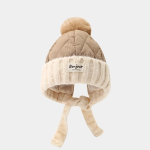 Detail view of winter kids trapper hat featuring faux fur pom and quilted stitch texture