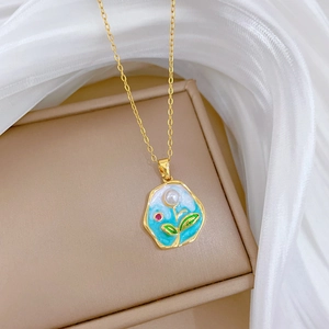 Detailed close-up of blue enamel floral pendant with pearls on a gold titanium necklace