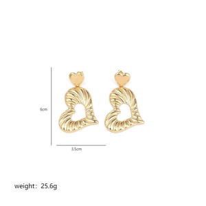 Exaggerated golden heart pendant earrings with irregular textured finish on white background
