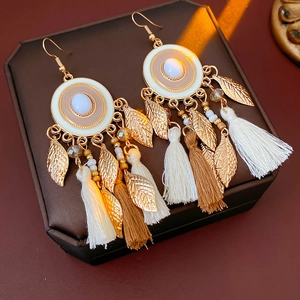 Detailed close-up of vintage enamel tassel earrings with gold leaf charms on a jewelry box