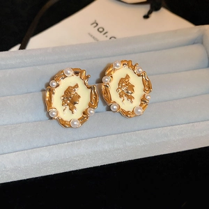 Close-up of vintage French cameo earrings with pearl accents on blue velvet background