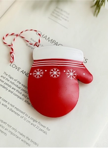 Detail eines roten Weihnachtshandschuhs mit weißen Schneeflocken auf Buchseiten