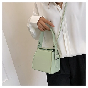 Detail of light green PU leather box bag with top handle and silver metal hardware