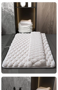 Close-up of white memory foam bath mat with diamond pattern on gray stone tiles