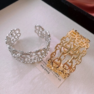Detail view of interlocking chain-link gold and silver bracelets with high-polish finish