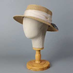 Chapeau de paille à haut plat avec ruban crème et accent doré sur un mannequin