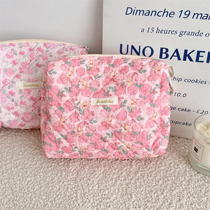 Detailed view of pink floral quilted makeup bags in small and large sizes on a soft carpet
