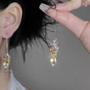 Macro detail of long silver tassel earrings with champagne aurora borealis crystals