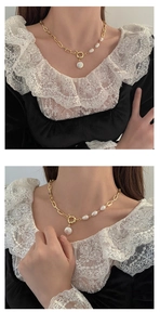 Detailed view of Baroque pearl pendant and gold chain necklace on a model wearing lace