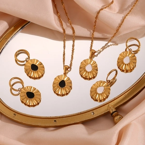 Detailed set of gold sunburst necklaces and earrings with black and white enamel teardrops