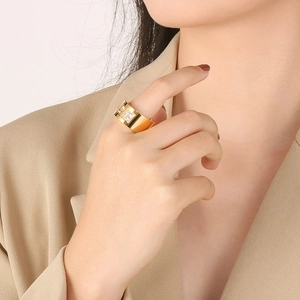 Close-up of a wide gold titanium ring featuring two square-cut sparkling zircons on a finger