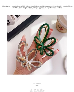 Close-up of marble pattern acetate butterfly hair claw with gold metal clip in hand