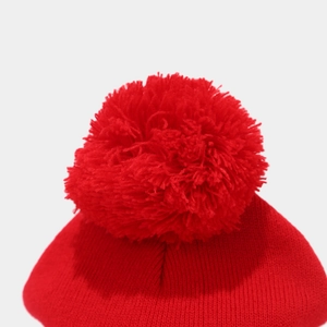 Close-up of the oversized red fluffy pom-pom and fine knit texture on the beanie top