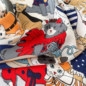 Detailopname van een lichte zijden sjaal met kleurrijke cartoon kattenprints en zachte textuur