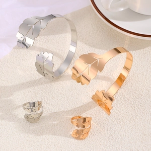 Detalle de brazaletes y anillos ajustables con diseño de hoja en acabados oro y plata