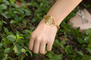 Outdoor view of golden double-layer Hamsa Hand charm bracelet on wrist in natural light