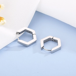 Détail macro de créoles géométriques hexagonales en argent avec une texture en métal brossé