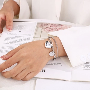 Fashionable double-layer silver heart bracelet shown on a model wearing white attire