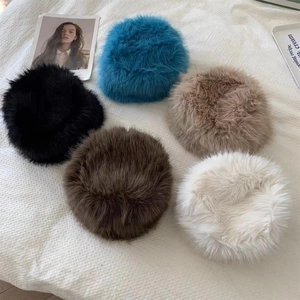 Detailed flat lay of faux fur winter bucket hats in five assorted colors on textured fabric