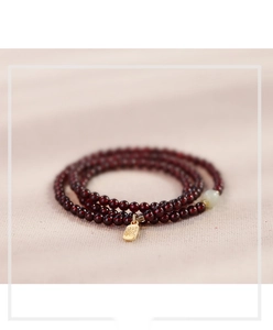 Detail of red garnet multi-wrap bracelet with golden Fu pendant and green jade bead