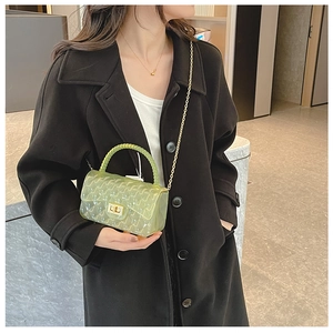Detail view of light green transparent jelly bag with gold chain strap and textured pattern