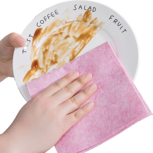 Absorbent pink coconut shell dishcloth removing stains from a white ceramic plate