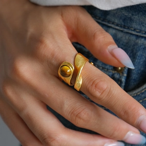Detailed view of vintage gold tiger eye stone double-layered open ring on denim fabric
