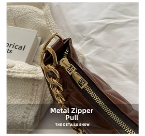 Detailed view of golden metal zipper and chain on brown quilted rhombic shoulder bag