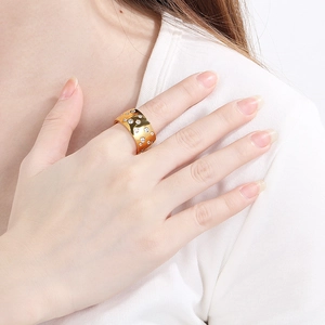 Close-up of a wide gold titanium ring with sparkling zircon stones on a female hand