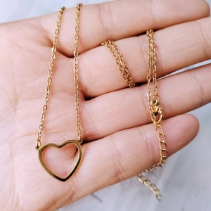 Close-up of a 18k gold heart pendant necklace with adjustable chain on hand