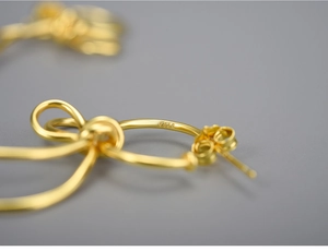 Macro shot showing the S925 sterling silver hallmark on the gold bow earring detail