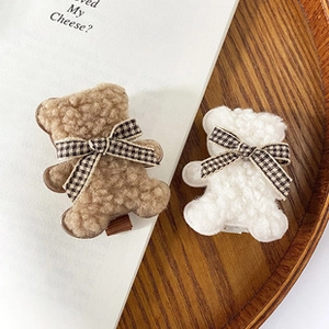 Detail of plush teddy bear hair clips with lamb wool texture and plaid ribbon bows
