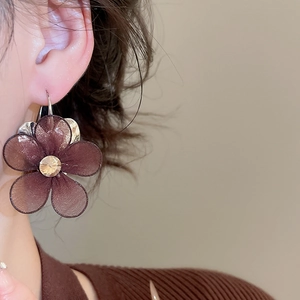 Detail of dark brown mesh flower earring with sparkling rhinestone center on model