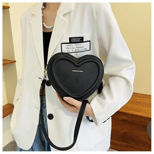 Dettaglio di una borsa a tracolla nera a forma di cuore con scritte dorate di moda