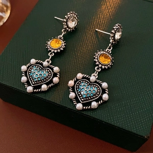 Macro detail of vintage floral pearl earrings with blue crystals on dark green box