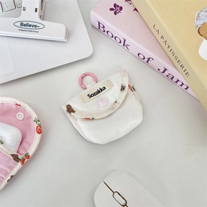 Detailed view of canvas earphone case with bear print and pink ring clasp on a desk