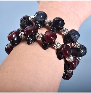 Close-up of gothic skull bead bracelets in dark red, black, and blue on wrist