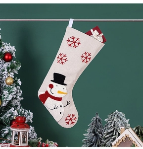 Détail d'une chaussette de Noël beige avec bonhomme de neige et flocons rouges