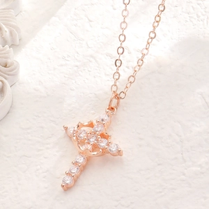 Macro shot of a rose gold crown pendant with sparkling zircons on a white textured background
