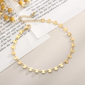 Detail of a gold heart link anklet with lobster clasp on vintage book background