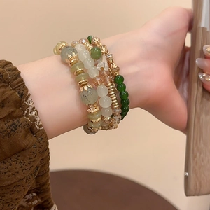 Detailed macro view of four-layer beaded bracelets with green crystals and gold accents