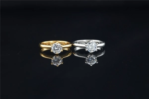 Detailed macro view of classic gold and silver moissanite rings on reflective black background