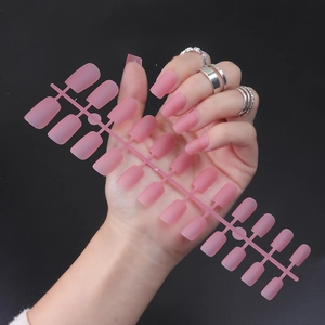 Long square matte pink false nails set with solid color finish on display stand