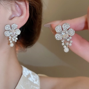 Detail of flower stud earrings with shimmering zircons and elegant pearl tassels