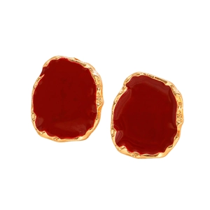 Detail of vintage irregular red enamel earrings with golden hammered metal edges